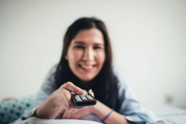Woman holding the TV remote control.